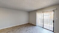 Located at 1500 East Broadway Road in Tempe, Arizona, this single-floor, three-bedroom, one-bathroom unit offers a practical and well-appointed layout. The combined kitchen and living room serves as the heart of the home, with the kitchen showcasing white shaker cabinets, quartz countertops, a grey tile backsplash, recessed lighting, and a full suite of stainless steel appliances including a refrigerator, range, microwave, and dishwasher. The living area features light wood-look flooring and a sliding glass door with vertical blinds that provides access to an outdoor space and brings in natural light. The three bedrooms are carpeted and include dedicated closets; the primary bedroom features a spacious walk-in closet with built-in shelving and hanging rods. The shared bathroom is cleanly finished with a wide dual-sink vanity, white cabinetry with brushed nickel hardware, a quartz countertop, and a combined tub and shower. A central hallway connects all rooms efficiently. Textured ceilings are consistent throughout, and neutral grey walls provide a clean, move-in-ready aesthetic throughout the entire unit.