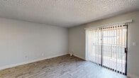 Located at 1500 East Broadway Road in Tempe, Arizona, this single-floor, three-bedroom, one-bathroom unit offers a practical and well-appointed layout. The combined kitchen and living room serves as the heart of the home, with the kitchen showcasing white shaker cabinets, quartz countertops, a grey tile backsplash, recessed lighting, and a full suite of stainless steel appliances including a refrigerator, range, microwave, and dishwasher. The living area features light wood-look flooring and a sliding glass door with vertical blinds that provides access to an outdoor space and brings in natural light. The three bedrooms are carpeted and include dedicated closets; the primary bedroom features a spacious walk-in closet with built-in shelving and hanging rods. The shared bathroom is cleanly finished with a wide dual-sink vanity, white cabinetry with brushed nickel hardware, a quartz countertop, and a combined tub and shower. A central hallway connects all rooms efficiently. Textured ceilings are consistent throughout, and neutral grey walls provide a clean, move-in-ready aesthetic throughout the entire unit.