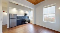 This 530 square foot apartment offers a thoughtful blend of compact living and modern design. The space features two bedrooms, one bathroom, and an open-concept layout that maximizes every inch of its single-floor plan. Rich wood flooring runs throughout, creating a warm and inviting atmosphere. The living areas are adorned with a striking wooden ceiling, adding character and height to the rooms.

Large windows in the bedrooms and living spaces flood the apartment with natural light, offering views of the surrounding urban landscape. The primary bedroom, measuring 110 square feet, provides a cozy retreat. The modern kitchen is a standout feature, boasting sleek white cabinetry, stainless steel appliances, and a stylish marble-look backsplash. Recessed lighting and under-cabinet illumination enhance the kitchen's functionality and aesthetic appeal.

The bathroom, while compact, is designed with a clean, minimalist approach, featuring a white palette and modern fixtures. Two hallways contribute to the efficient flow of the space, connecting the various rooms seamlessly. Despite its modest size, this apartment demonstrates how thoughtful design can create a comfortable and stylish living environment in an urban setting.