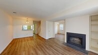 Located at 7660 Van Hoy Drive in Richmond, VA, this two-story home offers four bedrooms and two bathrooms across two well-organized floors. The main level features a welcoming living room with warm hardwood-style flooring, a textured ceiling, and a wood-burning fireplace framed by a classic dark surround. Built-in shelving flanks the fireplace, adding both character and storage. Natural light flows in through multiple windows, creating a bright and open atmosphere. The kitchen is efficiently laid out in an L-shape and equipped with warm wood cabinetry, dark granite-style countertops, and black appliances including a range, dishwasher, and refrigerator. A staircase connects the main level to the upper floor, where the bedrooms are carpeted for comfort. The spacious primary bedroom includes direct access to a full bathroom. Additional bedrooms are generously sized and offer easy access to the second full bathroom, which features tile flooring and a wood-toned vanity. A dedicated laundry room with side-by-side washer and dryer hookups adds everyday convenience. Throughout the home, textured ceilings and neutral tones provide a clean, versatile backdrop suited to a variety of interior styles.