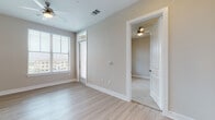Located on S Brook Dr in Leander, Texas, this single-story residence offers a well-designed layout with contemporary finishes and a bright, neutral aesthetic. The open-concept kitchen serves as a central highlight, outfitted with crisp white shaker cabinets, granite countertops, a subway tile backsplash, stainless steel appliances — including a refrigerator, range, microwave, and dishwasher — and a kitchen island with seating. Under-cabinet lighting adds both function and ambiance to the space. Light wood-style flooring flows through the main living and kitchen areas, creating a seamless, cohesive look. The bedrooms feature plush carpeting and large windows fitted with horizontal blinds that allow for ample natural light and privacy. Ceiling fans are present in multiple rooms, contributing to year-round comfort. The bathroom is finished with a white vanity, granite countertop, a glass-enclosed walk-in shower, and wood-style flooring, maintaining the clean, modern feel found throughout the residence. Neutral warm-beige tones on the walls complement the white trim and millwork, giving the entire space a polished yet inviting character. The overall design prioritizes functionality and modern comfort in a well-appointed Leander location.