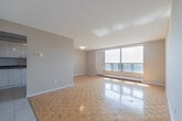 Located at 365 Kennedy Rd in Brampton, Ontario, this well-organized single-floor unit offers a practical and comfortable layout. The combined kitchen and living area forms the heart of the space, where the kitchen features white cabinetry, dark granite-style countertops, and stainless steel appliances including a refrigerator. Light-toned tile flooring runs through the kitchen, transitioning seamlessly into the living area. The living room is a highlight of the unit, characterized by its classic parquet hardwood flooring that adds warmth and texture to the space. Large windows along one wall flood the room with abundant natural light and offer open views of the surrounding Brampton cityscape, creating a bright and airy atmosphere. A baseboard heating unit runs beneath the windows, ensuring year-round comfort. The neutral grey walls throughout provide a clean, versatile backdrop. The bathroom is efficiently designed, featuring light tile flooring, a full bathtub and shower combo with white tile surround accented by a bold black tile border, a toilet, and a vanity. The overall design of the unit is clean and functional, making it a practical living space in a well-established Brampton neighbourhood.