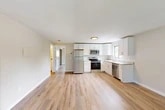 Located at 13–37 West Dr in New York Mills, NY, this single-floor, one-bedroom, one-bathroom unit offers a clean, modern aesthetic with thoughtful updates throughout. Light-toned hardwood flooring runs continuously across the entire space, creating a cohesive and bright atmosphere.

The open-concept kitchen and living area forms the heart of the unit. The kitchen is well-appointed with white shaker-style cabinetry, granite-look countertops, and a full suite of stainless steel appliances including a refrigerator, electric range, microwave, and dishwasher. A window above the sink allows natural light to fill the cooking area. The adjoining living space offers ample room for furniture arrangement and benefits from the open layout.

The generously sized primary bedroom includes a built-in open closet with a hanging rod, as well as a window that brings in natural outdoor views of surrounding greenery. Additional storage is provided by two closets elsewhere in the unit, one featuring classic louvered bi-fold doors. Baseboard heating is present in both the bedroom and living areas, ensuring comfort year-round.

The bathroom includes a full tub and shower surround in a clean white finish. Overall, the unit presents a fresh, move-in-ready interior with a neutral palette well-suited for a variety of décor styles.