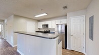 Located at 802 Jasmine Cove Cir in Simpsonville, SC, this well-appointed 3-bedroom, 2-bathroom single-floor residence offers a thoughtfully designed layout with a comfortable, functional feel throughout. The open-concept kitchen and living area serves as the heart of the home, featuring white shaker-style cabinetry, dark granite-style countertops with a peninsula breakfast bar, stainless steel appliances including a refrigerator, electric range, and microwave, and durable hardwood-style flooring. The living room is bright and spacious, boasting a vaulted tray ceiling, ceiling fan, recessed lighting, and double French doors that open to a private balcony, allowing natural light to fill the space. The generously sized primary bedroom includes a vaulted ceiling, ceiling fan, and hardwood-style flooring. The secondary bedrooms are finished with plush carpeting, ceiling fans, and natural light from bright windows, each offering closet access. With six closets total, storage is abundant throughout. Both bathrooms are clean and functional, featuring tub-shower combinations and wood-style flooring. A dedicated utility room and staircase round out the floor plan, completing this move-in-ready home.