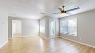 Located at 4659 Dawson Blvd in Atlanta, Georgia, this single-floor space offers a clean, functional layout with a neutral, modern aesthetic throughout. Light hardwood flooring runs consistently across all living areas, creating a bright and cohesive feel. The living area is well-proportioned, featuring a ceiling fan with integrated lighting and multiple windows dressed with white horizontal blinds that allow ample natural light to filter in. An additional room provides similar features, including its own ceiling fan, hardwood floors, and a window with blinds — suitable for use as a bedroom or flex space. A closet space with louvered bifold doors offers built-in shelving and includes hookups, suggesting in-unit laundry capability. The kitchen is equipped with stainless steel appliances, including a range, over-the-range microwave, and refrigerator, complemented by gray cabinetry and a white tile backsplash. The bathroom features a sleek vanity with a white countertop, gray cabinets with gold hardware, and a gold-framed mirror. Textured ceilings and consistent light gray wall tones tie the interior together, giving the space a tidy, move-in-ready presentation throughout.
