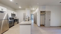 Located in Horizon City, TX, this thoughtfully designed single-story home offers three bedrooms and two bathrooms with a clean, contemporary aesthetic. Light wood-look flooring runs throughout, complementing the neutral palette of crisp white and soft gray tones.

The kitchen is a standout feature, equipped with stainless steel appliances, two-tone cabinetry—white uppers paired with gray lowers—granite countertops, and a central island with a double sink and a modern pull-down faucet, providing both functionality and style.

Both bathrooms are finished with granite-topped gray vanities and black matte fixtures. The primary bathroom features a dual-sink vanity with two round black-framed mirrors and stylish sconce lighting, while the secondary bathroom offers a single vanity with matching design elements.

The primary bedroom is a generously proportioned retreat with a ceiling fan, a dedicated closet, and French doors that invite natural light and outdoor access. The additional bedrooms are bright and comfortable, each featuring ceiling fans and windows with blinds. A dedicated walk-in closet provides added storage convenience. The home's cohesive modern finishes, abundant natural light, and efficient layout make it a well-appointed residence in the Horizon City community.