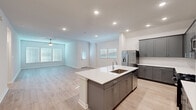 Located at 17003 Telge Road in Cypress, TX, this well-appointed single-story home offers a thoughtfully designed open-concept layout across five bedrooms and four full bathrooms. Light wood-look flooring flows throughout the entire home, complementing the clean, neutral color palette that gives the space a bright, modern feel.

The kitchen and living area form the heart of the home, showcasing a large center island with a white quartz countertop and integrated sink, sleek gray cabinetry, white subway tile backsplash, and stainless steel appliances including a refrigerator with ice maker, microwave, and range. Recessed lighting illuminates the kitchen, while the adjacent living room benefits from natural light through multiple windows and is finished with a ceiling fan overhead.

The five bedrooms are generously proportioned, each featuring light wood flooring, neutral walls, and window blinds that allow for adjustable natural light. The spacious primary bedroom includes a large walk-in closet with full-perimeter hanging rods offering ample storage. The four bathrooms feature gray vanity cabinetry, white quartz countertops, undermount sinks, and large mirrors.

A dedicated laundry room houses a full-size washer and dryer with overhead shelving. The attached garage provides substantial vehicle and storage space and is equipped with an automatic opener. This home presents a clean, contemporary aesthetic throughout.