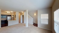 This two-story residence offers a practical and comfortable layout across both floors. The main level features an open living area with neutral-toned carpet, a structural column accent, and a staircase with wood-toned treads leading to the upper floor. A window allows natural light to brighten the space. Adjacent to the living area, the kitchen is outfitted with dark espresso cabinetry, granite-style countertops, a stainless steel refrigerator, gas range, and built-in microwave. A double-basin stainless steel sink is set into a center island, complemented by a chandelier overhead and access to a pantry closet. A half bath on the main level features hardwood-style flooring and clean, minimalist finishes.

The upper level hosts generously sized bedrooms with plush carpeting and ample natural light from multiple windows. The primary bedroom includes a walk-in closet equipped with wire shelving and hanging rods. A full bathroom on this level provides a vanity with a wide mirror, a tub-shower combination, and bright overhead lighting. A dedicated in-unit laundry area accommodates a full-sized top-load washer and dryer with overhead wire shelving for storage.