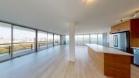 Located along the scenic Lake Merritt Path in Oakland, CA, this single-floor residence offers a refined modern aesthetic defined by clean lines, abundant natural light, and sweeping panoramic views of Lake Merritt and the surrounding cityscape. Expansive floor-to-ceiling sliding glass doors and large-format windows wrap the main living area, flooding the space with daylight and framing breathtaking vistas at every turn. Light-toned hardwood flooring runs continuously throughout, contributing to the open, airy character of the interior.

The open-concept living and dining area is generously proportioned, with a structural column providing subtle definition between zones while preserving the seamless flow of the layout. The kitchen is thoughtfully designed, featuring warm wood cabinetry with sleek hardware, white quartz countertops, a glass tile backsplash, stainless steel appliances including a French door refrigerator and dishwasher, and a deep undermount sink. An island with a waterfall-edge counter adds workspace and visual continuity.

Bedrooms open to balcony access through sliding glass doors, offering private outdoor space with sweeping views. Bathrooms are finished with floating wood vanities, white countertops, large mirrors, and glass-enclosed showers, maintaining the space's consistent modern sensibility throughout.