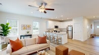 Located at 1000 Old Fayetteville Rd NE in Leland, NC, this two-story home offers a bright, modern interior defined by consistent light wood flooring, crisp white walls, and ceiling fans throughout. The open-concept main level seamlessly connects the living area and kitchen, creating an inviting, functional space. The living room features sliding glass doors that fill the room with natural light and provide access to the outdoors. The kitchen is well-appointed with white shaker-style cabinetry, granite countertops, stainless steel appliances — including a refrigerator, range, and microwave — and a large peninsula with seating, ideal for casual dining or entertaining. A full bathroom on the main level mirrors the home's clean aesthetic with white cabinetry, granite counters, and wood-look flooring. Upstairs, the primary bedroom suite is generously sized with an en-suite bathroom featuring a walk-in shower and granite vanity, as well as a spacious walk-in closet with wire shelving. An additional room serves well as a home office or flex space, bathed in natural light from a window. A dedicated laundry room with full-size washer and dryer adds everyday convenience. The home's consistent finishes and thoughtful layout make it a comfortable and practical residence.