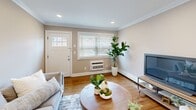Located at 1 Kowal St, Unit A7 in Clifton, NJ, this well-appointed one-bedroom, one-bathroom unit offers a thoughtfully designed single-floor layout that maximizes every inch of its comfortable footprint. The open-concept living and kitchen area serves as the heart of the home, with warm hardwood floors, crown molding, and recessed lighting creating a polished, cohesive ambiance throughout. The living room is bright and welcoming, with a large window that allows natural light to pour in, complemented by a front entry door with a glass panel detail. The kitchen is a standout feature, showcasing white shaker cabinetry, light granite countertops, a classic gray subway tile backsplash, and a full suite of stainless steel appliances including a gas range, microwave, dishwasher, and refrigerator. A peninsula with seating adds both functionality and style. The bedroom is generously sized with crown molding, recessed lighting, a ceiling fan, hardwood floors, and a large window with natural light. The bathroom offers a clean, neutral aesthetic with a tiled tub-shower combination and a bright window. Additional highlights include three closets for ample storage, an in-unit laundry area, and a connecting hallway that ties the layout together efficiently.