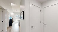 Located at 8404 229 St NW in Edmonton, Alberta, this well-appointed 2-bedroom, 1-bathroom unit offers a thoughtfully designed single-floor layout with modern finishes throughout. The open-concept kitchen and living area serves as the heart of the unit, featuring a striking quartz waterfall island with bar seating, dark wood cabinetry extending to the ceiling, and a full suite of stainless steel appliances. Light hardwood flooring flows seamlessly throughout the main living areas, enhancing the bright, airy atmosphere created by recessed lighting and crisp white walls. The primary bedroom is a comfortable retreat with a built-in sliding-door closet and a wall-mounted television, with a window offering views of the surrounding neighbourhood. The second bedroom is equally clean and functional, featuring a closet and wall-mounted TV. The full bathroom is finished with large-format marble-look porcelain tile flooring, a floating wood-toned vanity with an integrated white countertop, a full-size soaker tub with shower, and recessed lighting. The unit is part of a contemporary multi-storey building with stone and panel exterior cladding, glass-railed balconies, and landscaped surroundings.