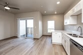 Located on Jasper Ave NW in Tiffin, Iowa, this thoughtfully designed one-bedroom, one-bathroom unit offers a practical and modern single-floor layout. Light hardwood flooring flows consistently throughout the entire space, lending a clean, cohesive aesthetic.

The heart of the unit is an open-concept area that seamlessly integrates the living room, dining room, and kitchen. The kitchen is well-appointed with white shaker-style cabinetry, light countertops, a full suite of stainless steel appliances including a refrigerator, range, dishwasher, and microwave, and a peninsula that defines the space without closing it off. A wall-mounted mini-split system provides efficient climate control.

A hallway connects the main living area to the private spaces, featuring a stylish sliding barn door as an architectural accent. The bedroom is a quiet, cozy retreat with neutral tones and ample natural light from a skylight above. Additional storage is provided by a dedicated closet. In-unit laundry access adds everyday convenience.

The bathroom is clean and functional, featuring a stand-alone shower unit, a white vanity with storage, and built-in wire shelving for organization. The overall palette of warm neutrals and white trim gives the space a fresh, move-in-ready feel.
