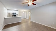 Located at 2480 Cypress Pond Rd in Palm Harbor, Florida, this one-bedroom, one-bathroom residence offers a thoughtfully designed single-floor layout that maximizes its compact footprint. Wood-look flooring flows consistently throughout the living spaces, complemented by neutral gray walls and white trim that create a clean, cohesive aesthetic.

The open-concept living, dining, and kitchen area forms the heart of the home. The kitchen features white shaker-style cabinetry, a white countertop peninsula with an undermount sink, and a full suite of stainless steel appliances including a refrigerator, electric range, microwave, and dishwasher. A skylight above the kitchen brings in additional natural light, while a pendant light accents the peninsula. Ceiling fans are present throughout, including in the living area and bedroom.

The bedroom is a well-proportioned retreat with a window offering views of the surrounding greenery, a ceiling fan, and access to two closets for ample storage. The bathroom is finished in a crisp, all-white palette with a single vanity featuring white cabinetry, a large mirror, and a full shower-tub combination. A dedicated laundry area adds everyday convenience. The entry area includes a window with blinds, allowing natural light to brighten the space.