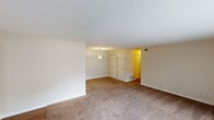 This single-floor residence offers a practical and comfortable layout designed to maximize livable space. The open living and dining area is generously sized, featuring warm beige carpet, clean white walls, and a textured ceiling. A pendant light fixture marks the dining zone, while a front entry door with adjacent vertical blinds provides access to natural light. The space flows seamlessly, creating a versatile environment for both relaxing and entertaining.

The galley-style kitchen is efficiently designed with white cabinetry lining both walls, dark countertops, and wood-look flooring. Black appliances, including an electric range and refrigerator, are complemented by a double basin sink, offering a functional cooking space with ample storage.

The bedrooms are carpeted and bright, each featuring large windows fitted with blinds that invite natural light while maintaining privacy. The rooms provide comfortable proportions suitable for a variety of furniture arrangements.

The bathroom includes a single-sink vanity with a marble-style countertop, a walk-in shower stall, and a toilet, all accented by a large mirror and a well-lit vanity light bar. Clean lines and neutral tones carry throughout the unit, giving the space a cohesive and move-in ready feel.