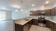 Located at 11813 East Broadway Avenue in Spokane Valley, WA, this single-floor unit offers a thoughtfully designed layout with modern finishes throughout. The kitchen serves as a central highlight, showcasing rich dark-toned cabinetry, granite countertops, a subway tile backsplash, and a full suite of stainless steel appliances including a range, microwave, dishwasher, and refrigerator. Pendant lighting and a chandelier above the peninsula add warmth and character to the space.

The living area features light wood-look flooring, large windows with blinds that allow generous natural light, and a private entry door. The bedrooms are carpeted for comfort and include baseboard heating, windows for natural light, and access to closet space. Dark-toned interior doors provide a contemporary contrast to the neutral wall tones throughout.

Two bathrooms serve the unit — one featuring a soaking tub and vanity with light stone-look countertops, and a second with a glass-door shower enclosure and wood-look flooring. The clean, neutral color palette and modern hardware selections create a cohesive and functional living environment well-suited for everyday comfort.