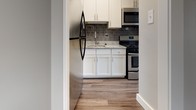 Located at 2000 Riverside Dr in Richmond, Virginia, this single-floor residence showcases a clean, modern aesthetic throughout. Wide-plank hardwood-style flooring in warm gray tones flows seamlessly across every room, tying the space together with a cohesive, contemporary feel.

The living area is bright and open, benefiting from a large window fitted with horizontal blinds that frames city views and allows abundant natural light to fill the room. The neutral palette of soft white and light gray walls enhances the sense of openness throughout.

The kitchen is thoughtfully appointed with crisp white shaker-style cabinetry, granite countertops, and a striking dark subway tile backsplash. Stainless steel appliances — including a gas range, built-in microwave, and refrigerator — complete the functional and stylish cooking space.

The bedroom is a well-proportioned, tranquil retreat with smooth walls and a sliding barn-style door that adds a modern design accent. An adjoining area provides a walk-in closet with built-in wire shelving, offering generous storage, alongside a bathroom vanity featuring white cabinetry and brushed nickel hardware.

Overall, the space presents a well-maintained, move-in-ready environment with updated finishes and a bright, airy ambiance throughout.