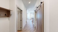 Located at 401 Haysland Rd SW in Huntsville, Alabama, this well-appointed single-story home offers 2 bedrooms, 3 bathrooms, and a thoughtfully designed layout. Light-toned hardwood-style flooring runs throughout the main living areas, complemented by crisp white walls and recessed lighting that create a clean, modern aesthetic. A standout feature of the hallway is a sliding barn door with black industrial hardware, adding a stylish contrast to the otherwise contemporary interior. The living area is bathed in natural light through large windows, with a curved wall accent near the entry door lending architectural interest. Both bedrooms are generously sized, each featuring ceiling fans and windows with outdoor views; the primary bedroom includes hardwood-style flooring while the secondary bedroom offers plush carpeting. The spacious primary bathroom is equipped with a double-sink granite vanity set in warm wood cabinetry, black matte fixtures, and a large walk-in glass shower with tile surround. A second bathroom mirrors this refined style with a single granite vanity and matching finishes. The primary suite also includes a dedicated walk-in closet outfitted with multi-tier wire shelving for ample storage. Throughout the home, consistent attention to modern detail and quality finishes create a comfortable, move-in-ready living environment.