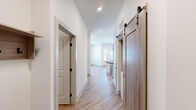 Located at 401 Haysland Rd SW in Huntsville, Alabama, this well-appointed single-story home offers 2 bedrooms, 3 bathrooms, and a thoughtfully designed layout. Light-toned hardwood-style flooring runs throughout the main living areas, complemented by crisp white walls and recessed lighting that create a clean, modern aesthetic. A standout feature of the hallway is a sliding barn door with black industrial hardware, adding a stylish contrast to the otherwise contemporary interior. The living area is bathed in natural light through large windows, with a curved wall accent near the entry door lending architectural interest. Both bedrooms are generously sized, each featuring ceiling fans and windows with outdoor views; the primary bedroom includes hardwood-style flooring while the secondary bedroom offers plush carpeting. The spacious primary bathroom is equipped with a double-sink granite vanity set in warm wood cabinetry, black matte fixtures, and a large walk-in glass shower with tile surround. A second bathroom mirrors this refined style with a single granite vanity and matching finishes. The primary suite also includes a dedicated walk-in closet outfitted with multi-tier wire shelving for ample storage. Throughout the home, consistent attention to modern detail and quality finishes create a comfortable, move-in-ready living environment.