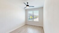 Located at 2403 Mall Dr in North Charleston, SC, this well-designed one-bedroom, one-bathroom unit offers a smartly utilized floor plan across a single level. The kitchen serves as the heart of the space, showcasing crisp white shaker-style cabinetry, dark countertops, a light blue subway tile backsplash, and a full suite of stainless steel appliances including a range, microwave, and refrigerator. A central island with a built-in sink and pendant globe lighting above adds both functionality and style. Light wood-style flooring runs throughout the main living and kitchen areas, contributing to a bright, cohesive aesthetic. The bedroom is a comfortable, carpeted retreat featuring a ceiling fan, natural light from a window with views of the surrounding area, and a dedicated closet for storage. The bathroom is finished in a clean, modern style with a tiled tub-shower combo, matte black fixtures and hardware, and a vanity with dark countertops that ties back to the kitchen's design language. White walls and recessed lighting throughout keep the space feeling open and airy. The overall design reflects a contemporary, low-maintenance style well-suited to efficient everyday living.