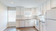 This single-story, 2-bedroom, 1-bathroom residence offers a well-organized layout across a compact yet efficiently utilized footprint. The kitchen serves as a standout feature, showcasing white shaker-style cabinetry extending to the ceiling, granite countertops, a subway tile backsplash, and white appliances including a range, dishwasher, and over-the-range microwave. Multiple windows allow natural light to fill the space, complemented by recessed lighting and wood-style flooring that flows throughout the kitchen and common areas.

The living area is bright and open, featuring neutral walls and the same wood-style flooring, providing a clean, versatile space. Both bedrooms are carpeted and equipped with ceiling fans. The primary bedroom includes a window with outdoor views and dedicated closet space, while the second bedroom also features a closet with built-in shelving. A hallway connects the main rooms and provides access to two closets for additional storage.

The bathroom is finished with a granite-topped vanity, white cabinetry, an undermount sink, and backlit mirrors, creating a polished, functional space. Neutral tones and consistent finishes throughout give the residence a cohesive, clean aesthetic.