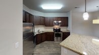 Located at 200 Citygreen Way in Chattanooga, Tennessee, this single-floor residence offers a thoughtfully designed layout with a variety of functional and comfortable spaces. The kitchen is a standout feature, equipped with rich dark-wood cabinetry, granite countertops, a tile backsplash, and a full suite of stainless steel appliances including a refrigerator, range, microwave, and dishwasher. Wood-look tile flooring adds warmth and durability to this space. The open living and dining area is generously sized, featuring plush neutral carpeting, a ceiling fan with light fixture, and a pendant light that defines the dining zone. A window with blinds invites natural light and provides views of the surrounding landscape. The bedrooms are carpeted and outfitted with ceiling fans, and at least one room enjoys a picturesque window view of the distant mountains and tree line. The bathrooms are well-finished, featuring dark-wood vanities with granite-style countertops, wood-look tile flooring, and bright vanity lighting. One bathroom includes a tub-shower combination, while another offers a walk-in shower. Interior doors throughout feature a classic two-panel design with brushed hardware, contributing to a cohesive and polished aesthetic.