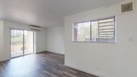 This single-floor studio offers a thoughtfully arranged open layout that maximizes every inch of its compact footprint. The main living area is finished with dark hardwood-style flooring that runs throughout, creating a cohesive and polished aesthetic against the crisp white walls. Natural light enters through a window fitted with horizontal blinds, while a sliding glass door leads to a private outdoor patio, further brightening the space. A wall-mounted mini-split air conditioning unit ensures year-round climate comfort, and a ceiling fan adds additional air circulation.

The kitchen is efficiently designed with a corner layout, featuring charcoal-gray cabinetry with brushed silver hardware, marble-patterned countertops, a stainless steel sink, a white electric range, and overhead cabinetry that maximizes storage. The bathroom is clean and functional, showcasing a full-size soaking tub with an overhead shower, a toilet, and a sink, all finished in white with consistent dark hardwood-style flooring. The overall ambiance of the studio is bright, minimal, and move-in ready, offering a practical and modern living environment.