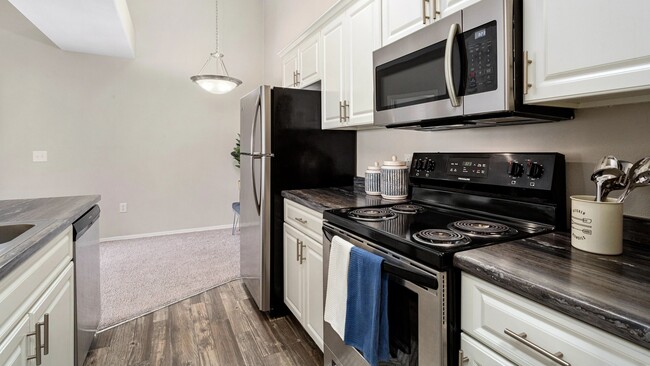 Our premium style floor plans feature kitchens with stainless steel appliances, white cabinetry and wood-style flooring. - Riverwood Apartments