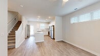 Located at 3100 Ascend Loop in Leland, NC, this two-story home offers three bedrooms, two full bathrooms, and a thoughtfully designed layout spread across two floors. The main level features an open-concept kitchen and living area finished with light wood-look flooring throughout. The kitchen is outfitted with white shaker cabinetry, granite countertops, a subway tile backsplash, stainless steel appliances including a range, microwave, and dishwasher, and a undermount sink. A practical under-stair closet provides additional storage, and a laundry area is conveniently located on this floor. The living room is bright and airy, with plantation shutters allowing natural light. Upstairs, the primary bedroom is generously sized and connects to a full bathroom featuring granite countertops, wood-look flooring, and a tub-shower combo. A walk-in closet with wire shelving accompanies the primary suite. Two additional carpeted bedrooms are located on the upper level, each with ceiling fans, ample natural light from large windows, and access to the hallway. The home features a neutral color palette, clean white trim, and panel-style interior doors throughout, creating a cohesive and modern aesthetic. A green backyard visible from the exterior completes the property.