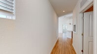 This thoughtfully designed two-bedroom, one-bathroom residence offers an efficient single-floor layout with modern finishes throughout. Light-toned hardwood flooring runs through the main living areas, kitchen, hallway, bathroom, and laundry room, lending a cohesive, clean aesthetic to the space.

The open living area is bathed in natural light from large sliding glass doors that provide outdoor views and access, complemented by a ceiling fan overhead. A central hallway connects all rooms and leads to the well-appointed kitchen, which features taupe flat-front cabinetry, granite countertops, a white subway tile backsplash, and a full suite of stainless steel appliances including a range, microwave, dishwasher, and side-by-side refrigerator with ice maker.

Both bedrooms are carpeted and receive ample natural light through multiple windows with blinds. The primary bedroom includes a spacious walk-in closet with built-in shelving. The bathroom is finished with granite countertops, gray cabinetry, and a framed mirror, with built-in open shelving nearby for additional storage. A dedicated laundry room houses a full-size washer and dryer, adding everyday convenience to this well-organized residence.