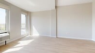 Located at 183-03 Hillside Ave in Jamaica, NY, this thoughtfully designed studio offers a bright, modern living experience within a compact and efficient single-floor layout. Light-toned hardwood flooring runs throughout, complementing the crisp white walls and creating a clean, contemporary aesthetic.

The open-plan kitchen and living area forms the heart of the space. The kitchen is well-appointed with white shaker-style cabinetry, a classic subway tile backsplash, white countertops, and a full suite of stainless steel appliances, including a refrigerator, electric range, built-in microwave, and dishwasher. Recessed lighting illuminates the kitchen area, while the adjacent living space benefits from abundant natural light streaming through large windows that offer open views of the surrounding Jamaica neighborhood.

The bathroom features a soaking tub with a clean, modern tile surround showcasing a striking contrast of white vertical tiles accented by a bold black horizontal band, paired with sleek chrome fixtures.

Two closets provide practical storage solutions throughout the unit. A wall-mounted electrical panel is neatly integrated near the entry. The space also includes a built-in air conditioning unit in the living area. The overall ambiance is bright, airy, and move-in ready, reflecting a modern design sensibility suited for urban living.