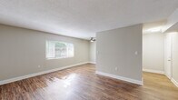 Located at 3232 Heritage Cir in Augusta, Georgia, this single-story home offers a thoughtfully updated interior with a clean, neutral palette throughout. The galley-style kitchen is a standout feature, showcasing white shaker cabinetry with modern brushed nickel hardware, granite-look countertops, a subway tile backsplash, and black appliances including an electric range and refrigerator. Hardwood-style flooring runs through the kitchen and extends into the main living areas, adding warmth and continuity to the open layout. The spacious living room benefits from a large picture window that draws in generous natural light, complemented by a ceiling fan overhead and a textured ceiling finish. Bedrooms are carpeted for comfort and feature multiple windows that further brighten each room, along with ceiling fans and closet storage. An additional room with hardwood-style flooring and a closet provides flexible use as a bedroom or office. The bathroom includes a tub-shower combination with clean white tile surround and a vanity with matching granite-look countertops. Throughout the home, consistent neutral-toned walls, white trim, and modern finishes create a cohesive and move-in-ready living environment.