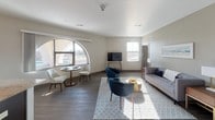 This thoughtfully designed single-floor residence offers a seamless blend of comfort and modern style. The open-concept living and dining area is a standout feature, anchored by a striking arched window that floods the space with natural light and frames outdoor views. Wood-look flooring flows throughout the main living areas, complementing the neutral, warm color palette. The living room provides generous space for both lounging and entertaining, with a dedicated dining nook nestled beside the arched window.

The kitchen is well-equipped and functional, featuring dark espresso cabinetry, light granite countertops, a classic tile backsplash, stainless steel appliances, and pendant lighting. A window above the sink allows for additional natural light and outdoor views while cooking.

The residence includes multiple bedrooms, each finished with plush carpeting, ample natural light from window blinds, and generous closet space. The primary bedroom connects to a private bathroom, while a second full bathroom serves the additional bedrooms. Both bathrooms are finished with light tile flooring, dark cabinetry, and granite vanities.

A convenient in-unit stacked washer and dryer is tucked discreetly into the living area, adding practicality to this well-rounded and cohesive living space.