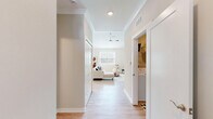 Located in Canton, Michigan, this well-appointed two-bedroom, three-bathroom single-floor home offers a thoughtfully designed layout with modern finishes throughout. The living room impresses with soaring vaulted ceilings and light wood-style flooring, creating an airy, open atmosphere. A built-in floating media wall with warm wood accents serves as a stylish focal point, complemented by bright windows that fill the space with natural light. The adjacent dining area features a striking pendant chandelier and a large sliding glass door that invites outdoor views and abundant sunlight. The kitchen is outfitted with crisp white shaker cabinetry, light quartz countertops, a soft gray subway tile backsplash, and stainless steel appliances, offering both function and style. The generously sized primary bedroom includes plush carpeting and two dedicated closets, providing ample storage. The bathrooms are finished with white vanities, quartz counters, and wood-look flooring, with one bath featuring a glass-enclosed shower. A dedicated laundry room houses a full-size side-by-side washer and dryer with overhead wire shelving. Clean neutral tones and consistent finishes throughout lend the home a cohesive, contemporary feel.