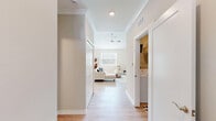 Located in Canton, Michigan, this well-appointed two-bedroom, three-bathroom single-floor home offers a thoughtfully designed layout with modern finishes throughout. The living room impresses with soaring vaulted ceilings and light wood-style flooring, creating an airy, open atmosphere. A built-in floating media wall with warm wood accents serves as a stylish focal point, complemented by bright windows that fill the space with natural light. The adjacent dining area features a striking pendant chandelier and a large sliding glass door that invites outdoor views and abundant sunlight. The kitchen is outfitted with crisp white shaker cabinetry, light quartz countertops, a soft gray subway tile backsplash, and stainless steel appliances, offering both function and style. The generously sized primary bedroom includes plush carpeting and two dedicated closets, providing ample storage. The bathrooms are finished with white vanities, quartz counters, and wood-look flooring, with one bath featuring a glass-enclosed shower. A dedicated laundry room houses a full-size side-by-side washer and dryer with overhead wire shelving. Clean neutral tones and consistent finishes throughout lend the home a cohesive, contemporary feel.