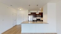 This single-floor residence is designed with a clean, contemporary aesthetic and a functional open-concept layout. The kitchen serves as a central highlight, featuring rich dark-wood cabinetry, granite countertops, and a full suite of stainless steel appliances, including a refrigerator, electric range, and microwave. A generously sized peninsula with a built-in sink and granite surface extends into the living area, illuminated by a pair of sleek pendant lights. Light wood-style flooring runs throughout the main living areas, lending warmth and continuity to the space.

The living room is bright and open, benefiting from natural light that enters through a sliding glass door leading to an outdoor patio. A ceiling fan adds comfort to the airy space. The bedrooms are carpeted, offering a softer feel, and each includes windows fitted with blinds that allow for controlled natural light.

Two bathrooms serve the unit. One features a walk-in shower with a dark-wood vanity and granite countertop, while the second includes a shower-tub combination. Both bathrooms are finished with light tile flooring and chrome fixtures. The overall palette throughout the unit is neutral and bright, creating a clean, move-in-ready atmosphere.