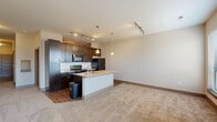 Located at 881 Third Ave SW in Carmel, Indiana, this thoughtfully designed single-floor residence offers 1 bedroom, 2 bathrooms, and a practical, efficient layout. The entrance hall features wood-look tile flooring that leads into the main living areas, with plush carpeting extending through the living room and bedroom.

The open-concept kitchen, dining, and living area serves as the heart of the home. The kitchen is outfitted with dark espresso cabinetry, a subway tile backsplash, granite countertops, and black appliances including a refrigerator, range, and built-in microwave. A central island with a sink and pendant lighting above provides additional prep space and a natural gathering point. Track lighting illuminates the entire open area.

The bedroom is a comfortable retreat, featuring carpet flooring, a ceiling fan, large windows that allow ample natural light, and access to an outdoor balcony with outdoor views.

The full bathroom includes light tile flooring, a soaking tub and shower combination, a dark-cabinetry vanity, and conveniently houses a stacked in-unit washer and dryer. Three closets throughout the unit provide generous storage, including a spacious walk-in closet with dual hanging rods. A second bathroom adds further convenience to the layout.