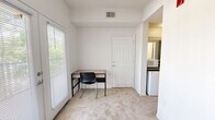 Located in Tallahassee, FL, this efficient one-bedroom, one-bathroom unit offers a practical and functional layout across a single floor. The bedroom features neutral, light-colored walls, carpeted flooring, a ceiling fan, and a louvered closet, providing a comfortable and organized personal space. The living area extends the functionality of the unit with carpeted flooring, a large window fitted with blinds that allows ample natural light to filter in, and convenient access to a compact kitchenette equipped with a mini-refrigerator and microwave. A dedicated entrance door leads directly into this space, adding privacy and accessibility. The bathroom is well-appointed with a full tub and shower combination featuring white subway tile surround, a grab bar for added safety, a toilet, and a vanity topped with a dark granite-style countertop and an integrated sink, complemented by a large mirror and tile flooring. The unit's clean white walls and neutral tones throughout create a simple, cohesive aesthetic that is easy to personalize. Overall, the space is thoughtfully designed to maximize utility within a compact footprint, making it a practical option in the Tallahassee area.