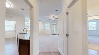 This thoughtfully designed one-bedroom, one-bathroom residence in Charlottesville, Virginia offers a comfortable and functional single-floor layout. The dual living areas are bright and open, featuring plush carpeting, crown molding, ceiling fans, and track lighting. Large windows with blinds invite abundant natural light, while a glass exterior door provides direct outdoor access and neighborhood views. The kitchen is well-equipped with rich dark wood cabinetry, granite countertops, stainless steel appliances including a range, microwave, refrigerator, and dishwasher, all set atop wood-look tile flooring. Pendant lighting above the sink adds a refined touch. The spacious bedroom features soft carpeting, vaulted ceilings, and generous natural light, with easy access to a dedicated closet. The full bathroom showcases dark wood vanity cabinetry, granite countertops, a large mirror, and wood-look tile flooring, offering a clean and polished aesthetic. A dedicated laundry area includes a full-size top-loading washer and dryer with overhead shelving. The overall ambiance is clean, neutral, and move-in ready, making this residence a practical and attractive option in the heart of Charlottesville.