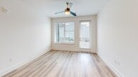 Located at 523 N Spring St in Greensboro, NC, this thoughtfully designed one-bedroom, one-bathroom residence offers a clean, modern aesthetic across a single well-organized floor. Light wood-style flooring runs throughout, creating a warm, cohesive feel from room to room. The open-concept kitchen and living area serves as the heart of the home, featuring crisp white shaker cabinetry extending to the ceiling, a light blue kitchen island with an undermount sink and pendant lighting, a subway tile backsplash, and a full suite of stainless steel appliances including a refrigerator, range, and microwave. The living area is bright and airy, enhanced by large windows fitted with white horizontal blinds and a ceiling fan, with access to an outdoor balcony that brings in views of the surrounding neighborhood. The bedroom is a comfortable, well-lit retreat with its own large window, a ceiling fan, and a dedicated closet. The bathroom is a standout feature, finished with wood-look flooring, white shaker vanity cabinetry, a clean white countertop, and a glass-enclosed walk-in shower adorned with large-format marble-look tile. Recessed lighting and crisp white walls throughout contribute to an overall ambiance that is bright, contemporary, and move-in ready.