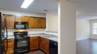 Located at 3001 Stone Carriage Cir in Fayetteville, NC, this single-story home offers a well-designed layout with a practical mix of flooring, finishes, and functional spaces throughout. The kitchen is equipped with warm-toned wood cabinetry, granite-style countertops, a built-in microwave, black appliances including a range and dishwasher, and a double sink — all illuminated by a skylight overhead. A breakfast bar connects the kitchen to the open living and dining area, which features rich dark hardwood-style flooring, a textured ceiling, and ceiling fan, creating a welcoming, open atmosphere. The bedrooms are carpeted for comfort, each featuring ceiling fans and ample natural light from window treatments with blinds. One bedroom includes a spacious walk-in closet with wire shelving, offering generous storage. The bathrooms are outfitted with tub-shower combinations and wood-style flooring, finished with clean, neutral tones. Throughout the home, neutral cream-colored walls provide a versatile backdrop. The property is surrounded by mature trees, adding a sense of privacy and natural greenery to the outdoor environment.