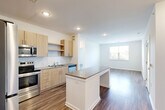 Located at 15151 Mattawoman Dr in Brandywine, MD, this thoughtfully designed 2-bedroom, 2-bathroom residence offers a comfortable and modern single-floor layout. The open-concept living, dining, and kitchen area serves as the heart of the home, featuring warm light wood cabinetry, granite countertops, a subway tile backsplash, and a full suite of stainless steel appliances including a refrigerator, range, microwave, and dishwasher. A central kitchen island provides additional prep and dining space. Wood-style flooring flows consistently throughout the entire residence, enhancing the clean, contemporary aesthetic. Recessed lighting illuminates the main living area, which connects seamlessly to a bright living room with natural light from a large window overlooking lush greenery. Both bedrooms are generously sized, each featuring windows with outdoor views of surrounding foliage, and are serviced by six closets total, including walk-in closet storage with wire shelving. The primary bathroom offers a dual-sink granite vanity with modern light wood cabinetry. Additional conveniences include a dedicated laundry area. The residence presents a bright, neutral palette throughout, creating a clean and move-in-ready living environment.