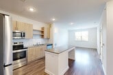 Located at 15151 Mattawoman Dr in Brandywine, MD, this thoughtfully designed 2-bedroom, 2-bathroom residence offers a comfortable and modern single-floor layout. The open-concept living, dining, and kitchen area serves as the heart of the home, featuring warm light wood cabinetry, granite countertops, a subway tile backsplash, and a full suite of stainless steel appliances including a refrigerator, range, microwave, and dishwasher. A central kitchen island provides additional prep and dining space. Wood-style flooring flows consistently throughout the entire residence, enhancing the clean, contemporary aesthetic. Recessed lighting illuminates the main living area, which connects seamlessly to a bright living room with natural light from a large window overlooking lush greenery. Both bedrooms are generously sized, each featuring windows with outdoor views of surrounding foliage, and are serviced by six closets total, including walk-in closet storage with wire shelving. The primary bathroom offers a dual-sink granite vanity with modern light wood cabinetry. Additional conveniences include a dedicated laundry area. The residence presents a bright, neutral palette throughout, creating a clean and move-in-ready living environment.