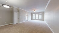 This single-floor residence offers a thoughtfully designed layout with a range of refined finishes throughout. The open living area is generously proportioned, featuring warm neutral carpet, crown molding, and a ceiling fan, all bathed in natural light from a bank of windows fitted with white blinds. Decorative columns with built-in shelving visually define the transition between the living space and the kitchen, adding a touch of architectural character. A pendant light fixture anchors the dining area nearby.

The kitchen is outfitted with dark cabinetry, granite countertops, and stainless steel appliances including a range and over-the-range microwave, complemented by hardwood-style flooring. A separate room features elegant French doors topped with an arched transom window, allowing natural light to pour in.

The bedroom is a comfortable, carpeted retreat with a ceiling fan and a window providing soft, natural light. The bathroom is well-equipped with dark espresso cabinetry, a white countertop, a large mirror framed by vanity lighting, and a bathtub/shower combination. An additional bathroom area features an L-shaped vanity with ample counter space and mirror coverage. Crown molding and consistent neutral tones unify the space, creating a clean, cohesive aesthetic throughout.