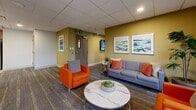 Located at 900 Carnarvon Street in New Westminster, BC, this single-floor amenity space offers a well-rounded communal environment designed for both relaxation and recreation. The layout is thoughtfully organized into distinct functional zones, providing residents with a variety of options for leisure and social gatherings.

The kitchen is outfitted with warm wood-grain cabinetry, white quartz countertops, and a clean subway tile backsplash. Stainless steel appliances — including a full-size refrigerator, built-in dishwasher, microwave, and induction cooktop — are integrated throughout, while light-toned floor tiles lend a bright, hygienic finish to the space.

The living room area features a wall-mounted flat-screen television, a marble-top console table, and comfortable seating that includes a grey sofa with orange accent pillows and a coordinating armchair. A round marble coffee table anchors the space, while patterned carpeting and large windows with outdoor views add warmth and natural light.

The games room is generously sized, accommodating a pool table, an air hockey table, and a ping-pong table. Large windows on multiple walls flood the room with daylight and offer open views of the surrounding cityscape. The space is finished with recessed lighting, a drop ceiling, and neutral carpeting, creating a casual and inviting atmosphere throughout.