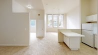This 1-bedroom, 1-bathroom residence is thoughtfully designed across a single floor, offering a comfortable and functional living environment. The space is immediately welcoming, featuring impressively tall ceilings that amplify the sense of openness throughout the main living area. Large, multi-pane windows flood the interior with abundant natural light and provide pleasant outdoor views, enhancing the bright, airy ambiance that defines the home.

The kitchen is efficiently laid out in an L-shape configuration and is equipped with white cabinetry reaching toward the ceiling, a smooth-surface electric range, a dishwasher, and a single-basin sink. A built-in peninsula adds additional counter space and flows naturally into the adjoining living area, which is finished with plush carpeting and a ceiling fan for year-round comfort.

A built-in desk or counter unit near the living space provides a practical workspace or storage area. The bedroom continues the light and open aesthetic, with carpeted flooring, a ceiling fan, and easy access to additional closet or utility space through interior doors.

The full bathroom is cleanly finished in white, featuring a tub and shower combination with accessible grab bars, a single-sink vanity with storage below, a toilet, and tile flooring — practical and well-maintained throughout. Overall, this residence offers a clean, functional, and inviting living environment.