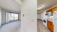 Located at 1555 Homer Rd in Winona, MN, this two-bedroom, one-bathroom unit offers a well-organized single-floor layout designed for comfortable everyday living. The entrance leads into a hallway that connects the main living areas, with light switches and utility access conveniently positioned near the entry point.

The living room is generously sized, featuring plush carpeting, a textured ceiling, and a sliding glass door that opens to a private balcony. The balcony overlooks a landscaped courtyard with mature trees and neighboring buildings, offering a pleasant outdoor retreat.

The galley-style kitchen is efficiently laid out with warm oak cabinetry lining both walls, light countertops, wood-look vinyl plank flooring, and white appliances including a range and refrigerator. A pass-through area connects the kitchen to the living space.

Both bedrooms are carpeted and bright, each featuring baseboard heating and natural light from windows with views of the surrounding grounds. The primary bedroom offers a notably spacious feel, while the second bedroom includes sliding wood-panel closet doors. Additional storage is well-served by four closets throughout the unit.

The bathroom is clean and functional, featuring a tub/shower combination, tile flooring, and a vanity with light countertops. Overall, the unit presents a practical and comfortable layout in a residential Winona neighborhood.