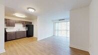 Located at 3600 Ely Pl SE in Washington, DC, this two-bedroom, one-bathroom unit offers a practical and well-organized single-floor layout. The open living area is a highlight, featuring light hardwood-style flooring and a full wall of floor-to-ceiling windows dressed with vertical blinds, flooding the space with natural light and offering views of the surrounding courtyard and neighborhood. The living area flows seamlessly into the kitchen, which is equipped with dark espresso cabinetry extending to the ceiling, a black gas range, black refrigerator, and a single-basin sink — all set atop matching hardwood-style flooring. Both bedrooms are carpeted for comfort and feature windows that bring in natural light. The primary bedroom includes a walk-in closet with built-in shelving, while the second bedroom offers a standard closet. Three closets in total provide ample storage throughout the unit. The full bathroom is finished with clean white square wall tiles, a soaking tub with overhead shower, a pedestal sink, and classic hexagonal floor tile. The bright, neutral color palette and clean finishes throughout give the space a fresh, move-in-ready feel.