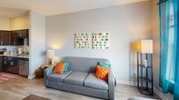 This 1070 square foot apartment in Kent, OH, offers a thoughtfully designed living space with 4 bedrooms and 2 bathrooms. The open-concept kitchen is a highlight, featuring dark wood cabinetry, stainless steel appliances, and granite countertops. A spacious island with seating provides additional prep space and casual dining options. The living room is bright and inviting, with a comfortable gray sofa, colorful accent pillows, and vibrant wall art that adds personality to the space. Large windows allow natural light to flood the area, creating an airy atmosphere. The bedrooms are well-appointed, with the primary bedroom measuring 140 square feet. Each room offers ample closet space and is decorated with a mix of modern and playful elements. The bathrooms showcase a contemporary design with glass shower enclosures, granite vanity tops, and stylish fixtures. Throughout the apartment, you'll find a cohesive color palette of neutrals accented with pops of blue, orange, and yellow, creating a harmonious and lively living environment. The apartment's layout is efficient, maximizing the use of space while maintaining a sense of openness and flow between rooms.