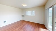 Located at 10913 West 6th Avenue in Airway Heights, WA, this one-bedroom, one-bathroom residence offers a well-designed single-level layout that maximizes its compact footprint. The open-concept living and kitchen area forms the heart of the home, featuring rich hardwood-style flooring that extends throughout. The kitchen is equipped with black appliances, including a refrigerator, range, microwave, and dishwasher, complemented by warm wood cabinetry and a peninsula with a double-basin sink that provides additional prep and storage space. Natural light flows into the living area through a large window and a sliding glass door that opens to a private balcony, offering outdoor views. A wall-mounted HVAC unit provides climate control for the main living space. The bedroom is a comfortable, carpeted retreat with a ceiling fan, a baseboard heater, and a window that brings in natural light. Two closets provide generous storage throughout the unit. The bathroom features a full tub-and-shower combination equipped with accessibility grab bars and a handheld showerhead. Additional conveniences include a dedicated laundry area and hardwood-style flooring in the main living spaces, creating a cohesive and functional living environment.
